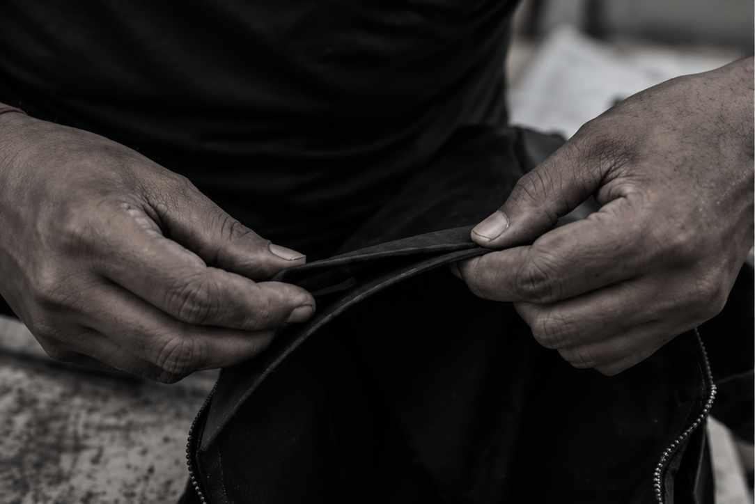 Artisan precision-stitching reclaimed rubber material with an industrial sewing machine